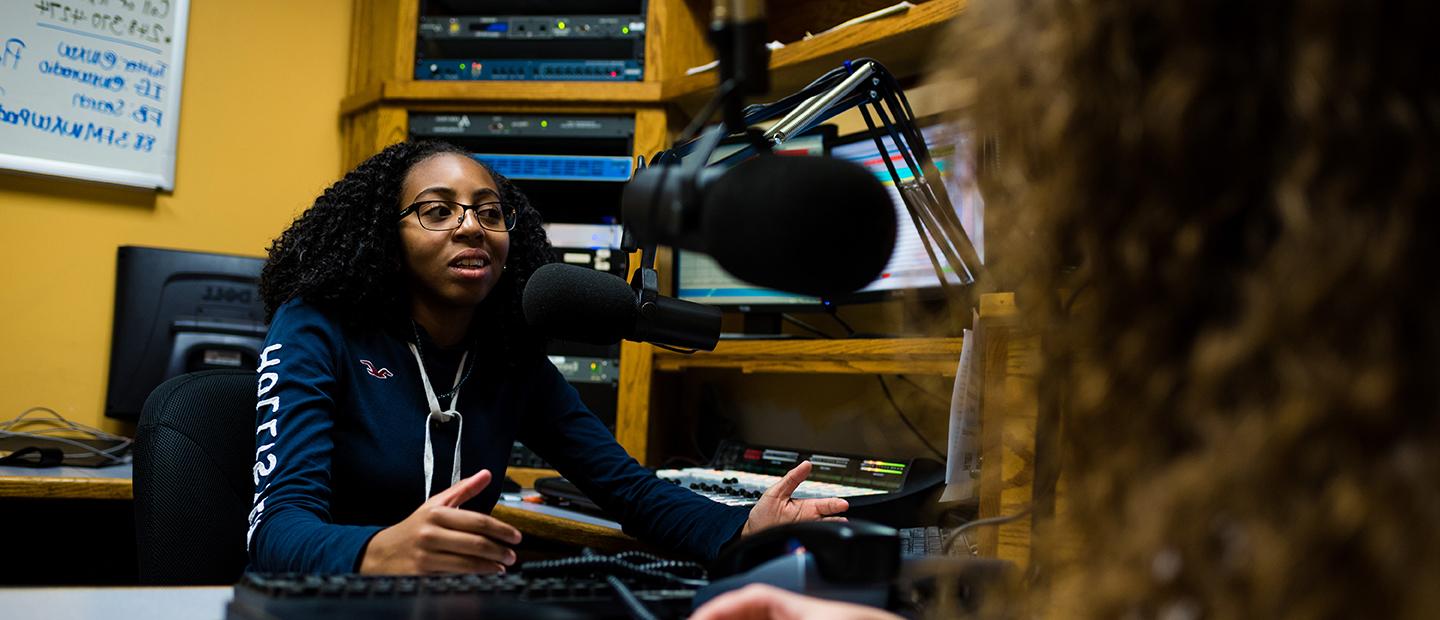 radio announcer at a microphone interviewing a guest