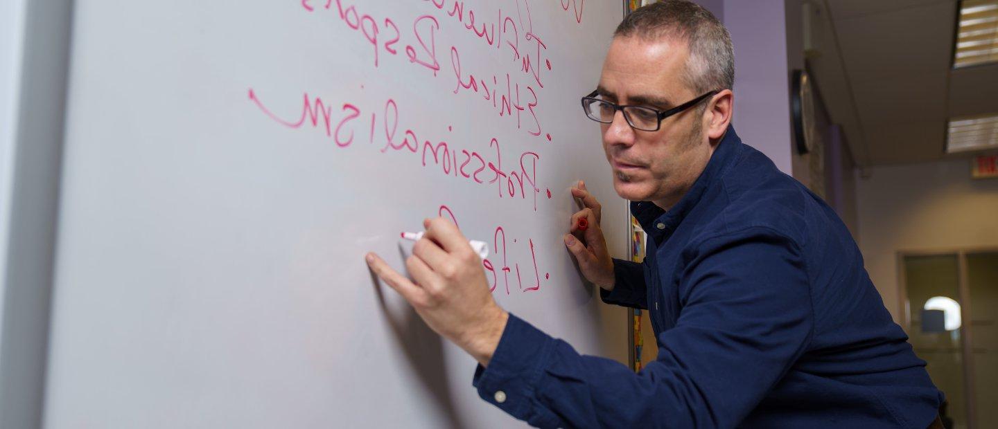 A professor writing on a white board.